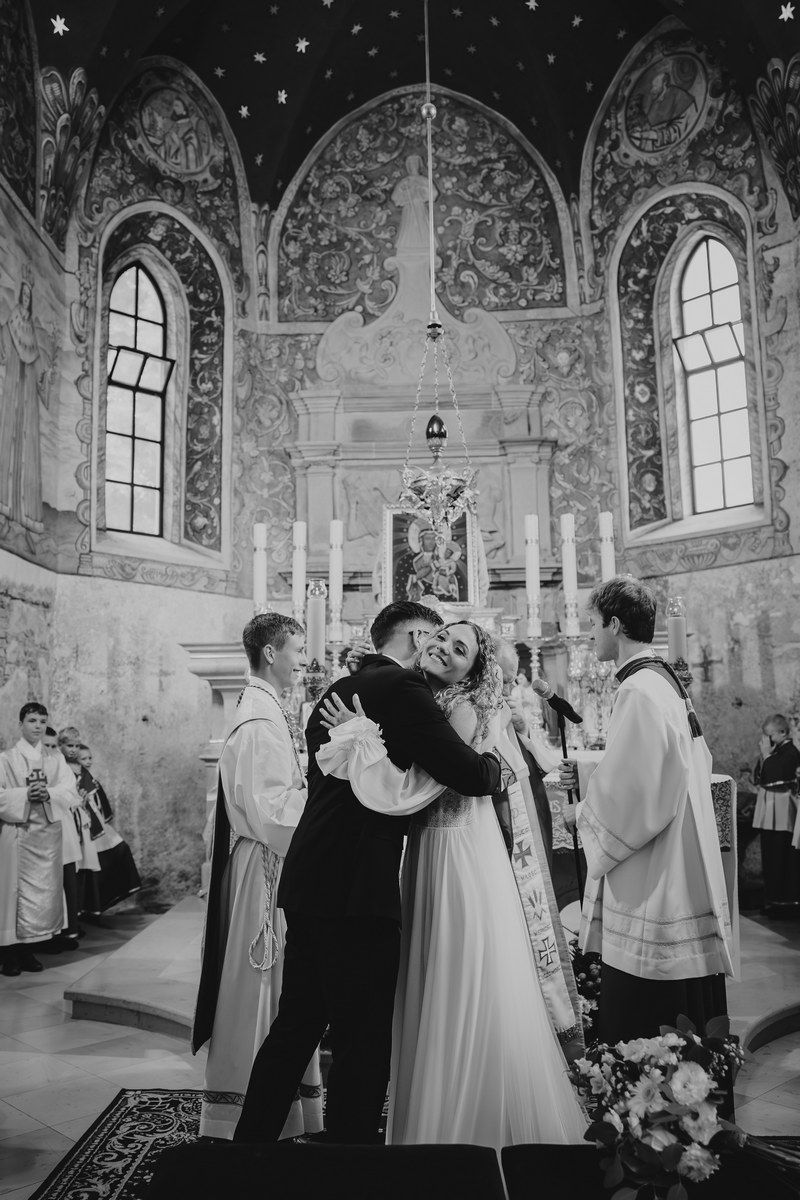 Para młoda czule się przytula po przysiędze małżeńskiej w kościele