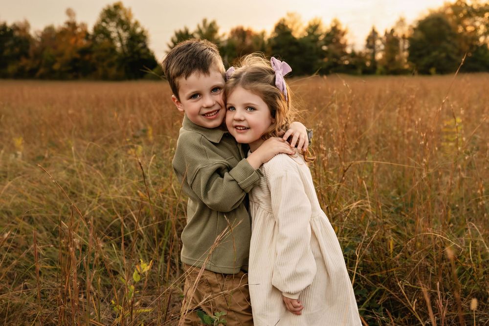 A loving family moment captured during golden hour in a rustic field at sunset.