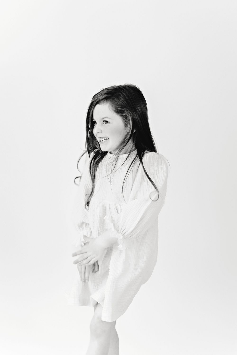 High key portrait series showing a young girl in white clothing against a white background with dynamic poses.