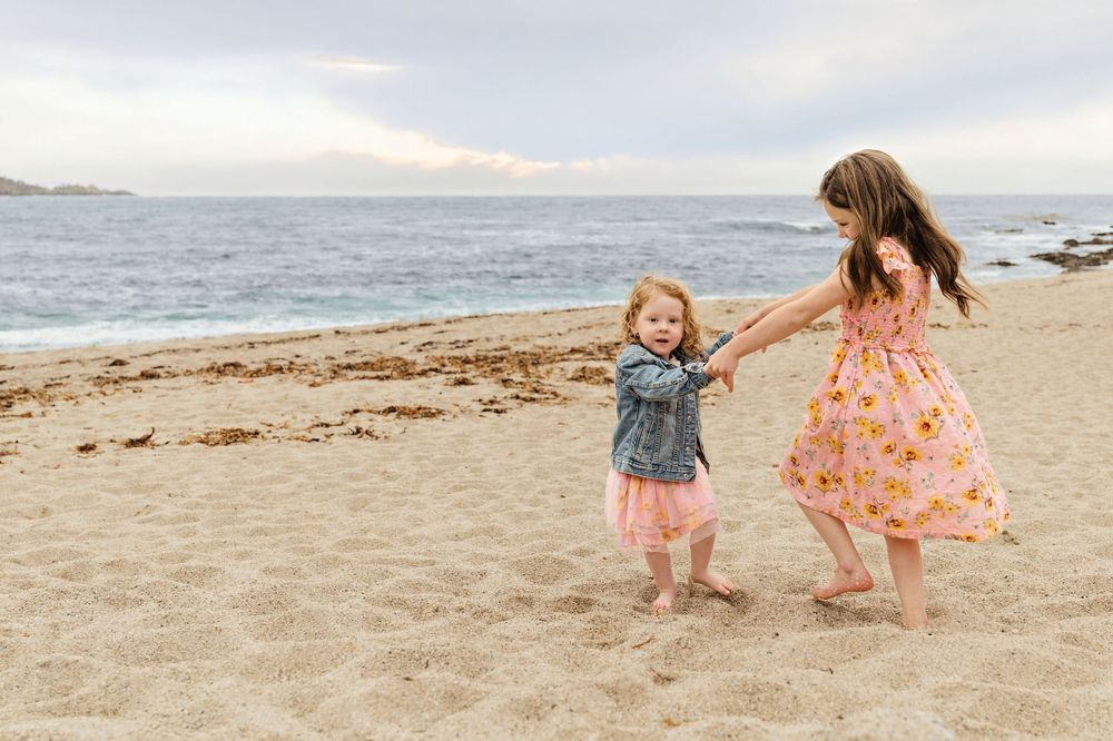Children play and walk together on a scenic sandy beach at sunset during a summer evening.