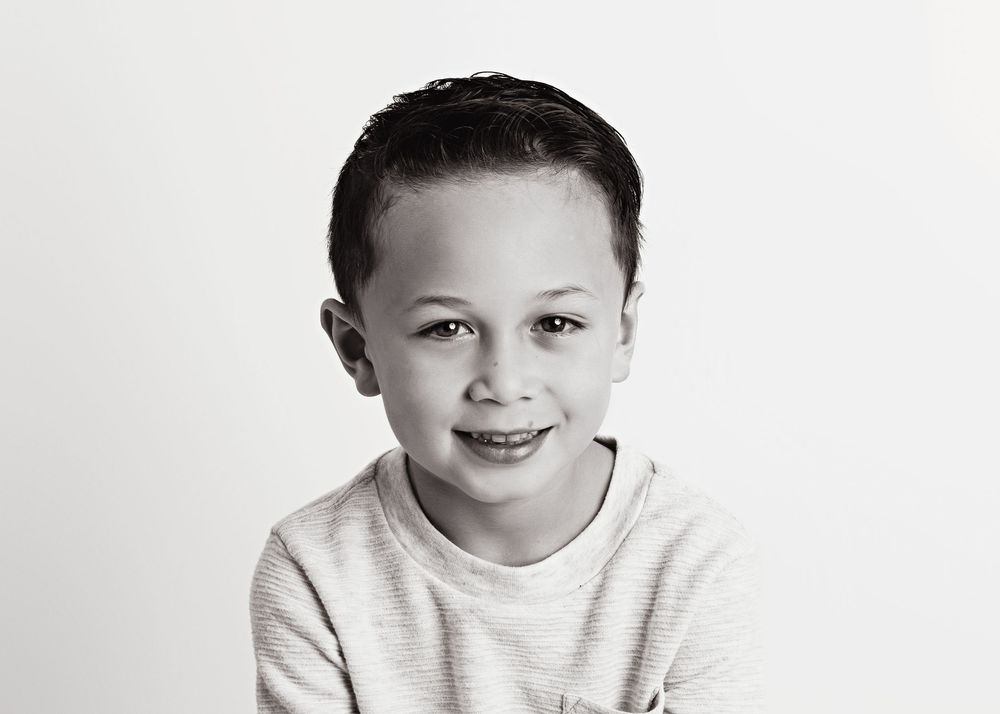 Black and white portrait of child in casual white sweater on simple background.