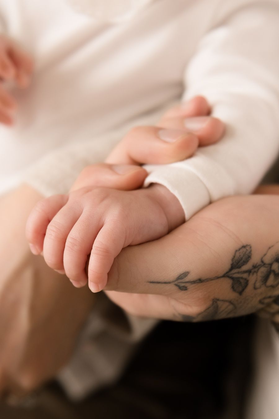 A close-up photo of a baby's small hand gently resting on dad's arm.