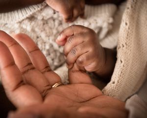 Close up of a baby's tiny hand grasping an adult finger.