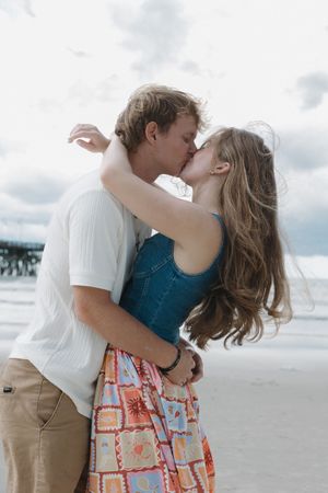 Romantic couple sharing an intimate moment on a sandy beach.