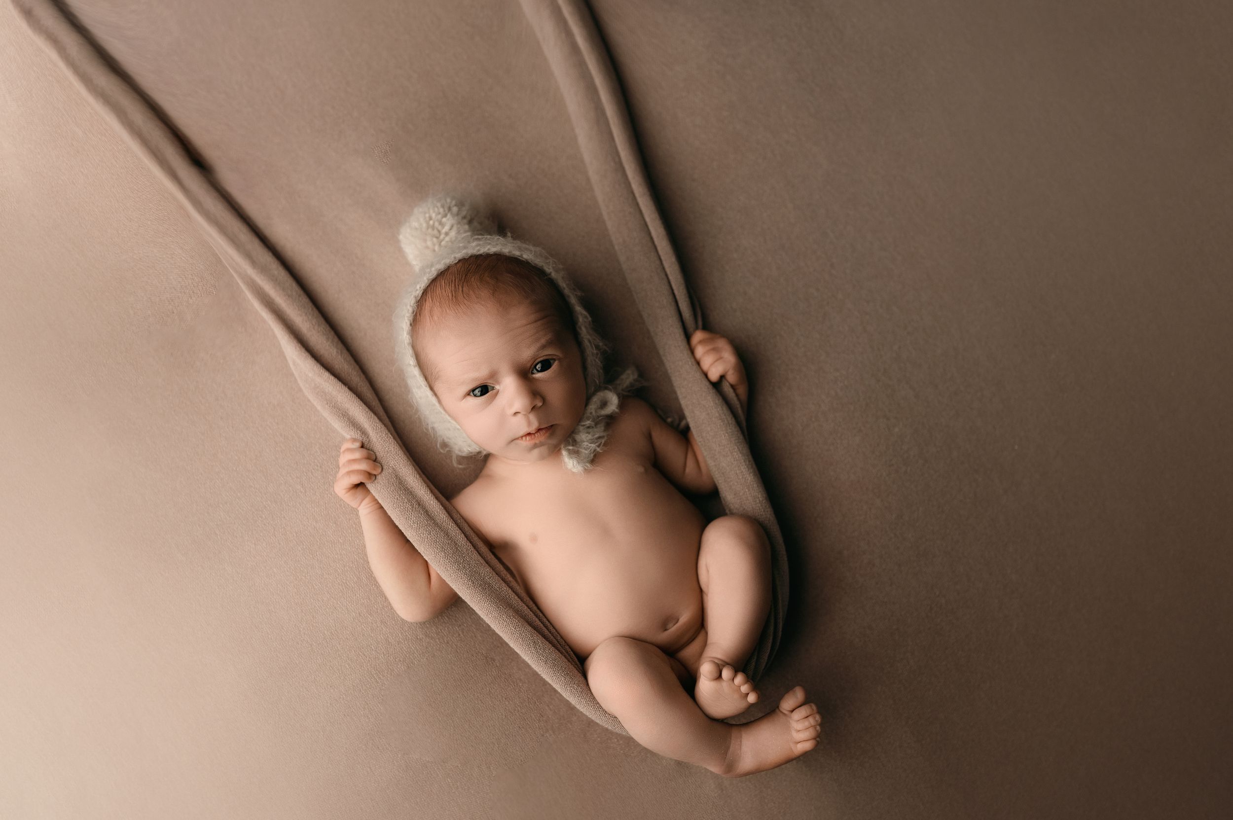 Collection of minimalist newborn portraits against warm neutral background.