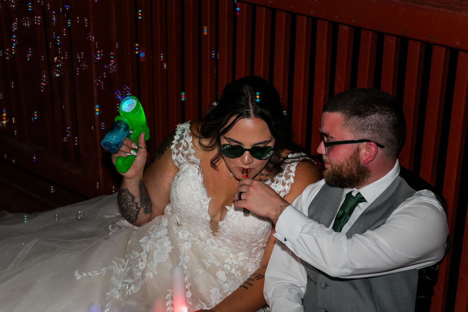 People in wedding attire having fun with water guns and squirt bottles at a party.