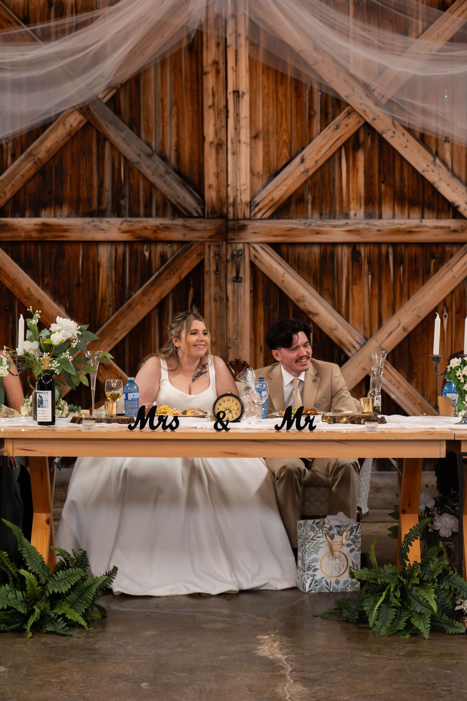 Newlywed couple showing off rings and embracing in white wedding attire.