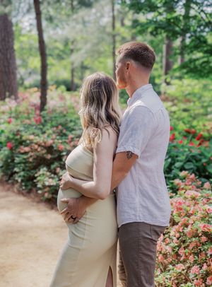 A couple embraces on a garden path surrounded by blooming flowers.