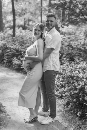 A couple shares intimate moments on a garden path surrounded by greenery.