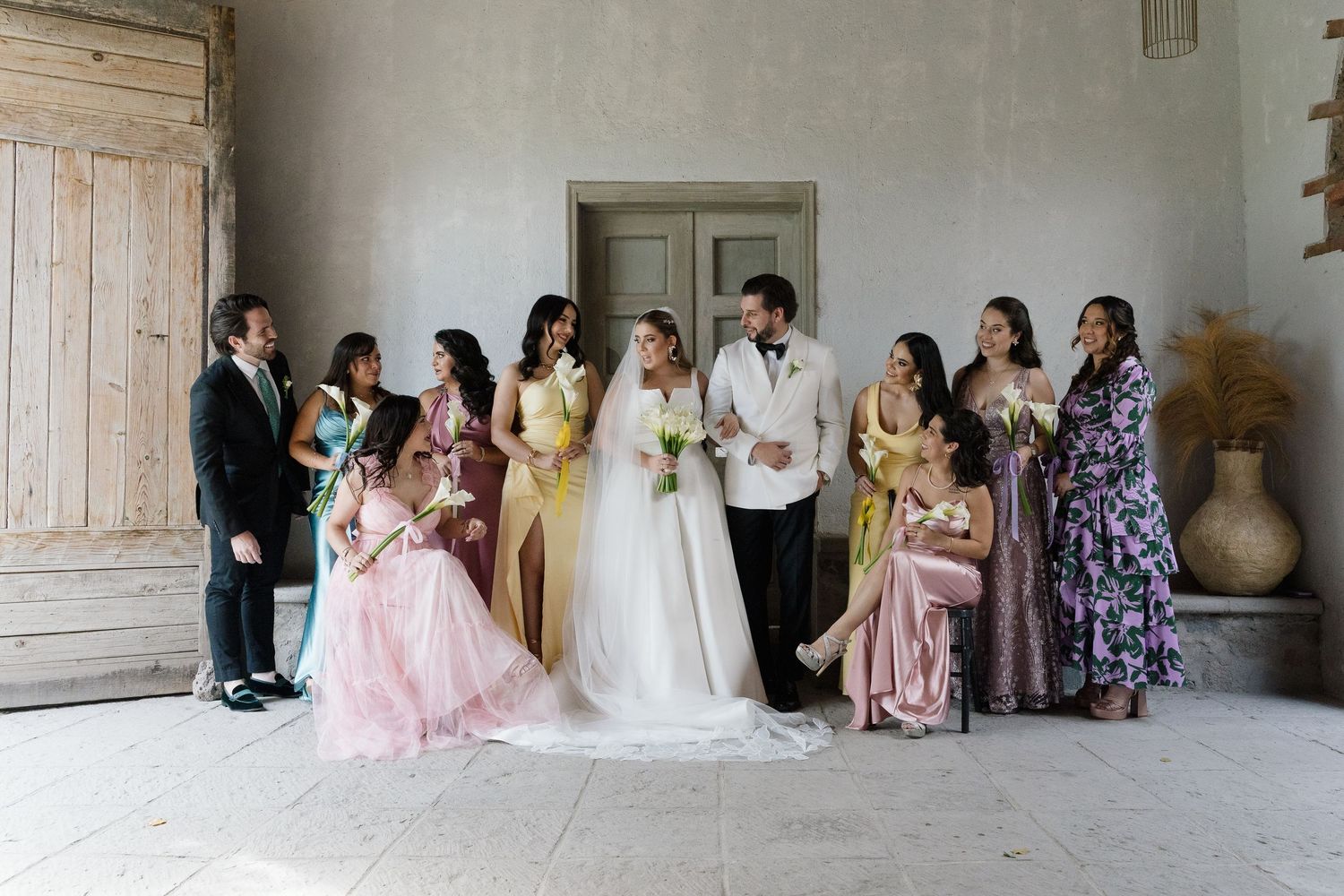 Wedding party gathered in an elegant rustic room with vintage wooden doors.