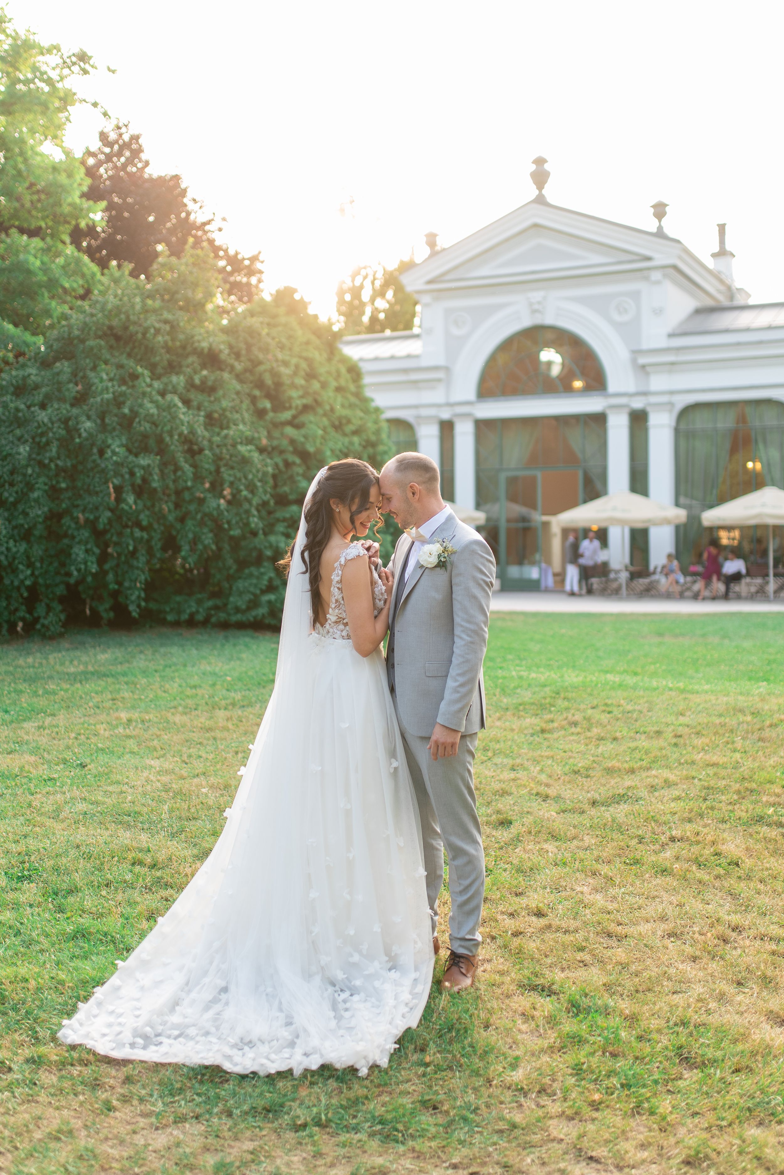Bride and groom sharing a kiss at golden hour outside a grand white pavilion venue.