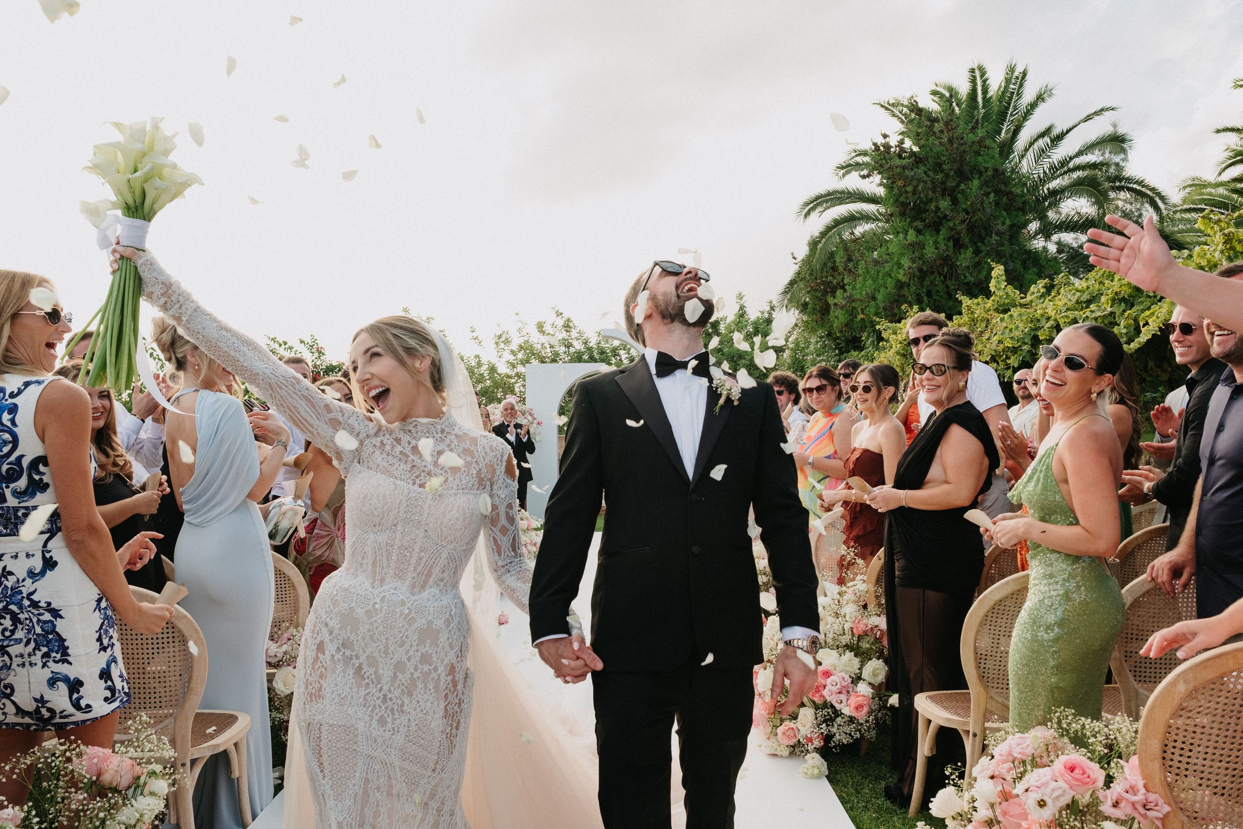 Pareja caminando de la mano de espaldas el día de su boda en el campo de césped de la finca Casal Santa Eulàlia de Mallorca.