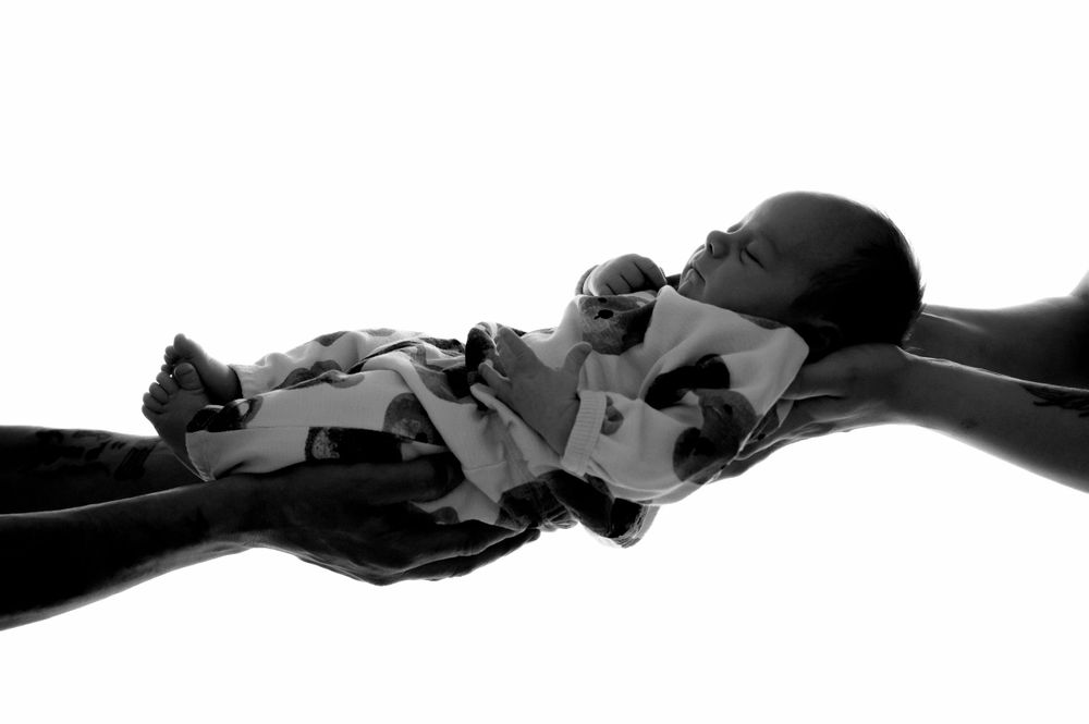 Artistic black and white silhouette of a sleeping infant wrapped in textured fabric.