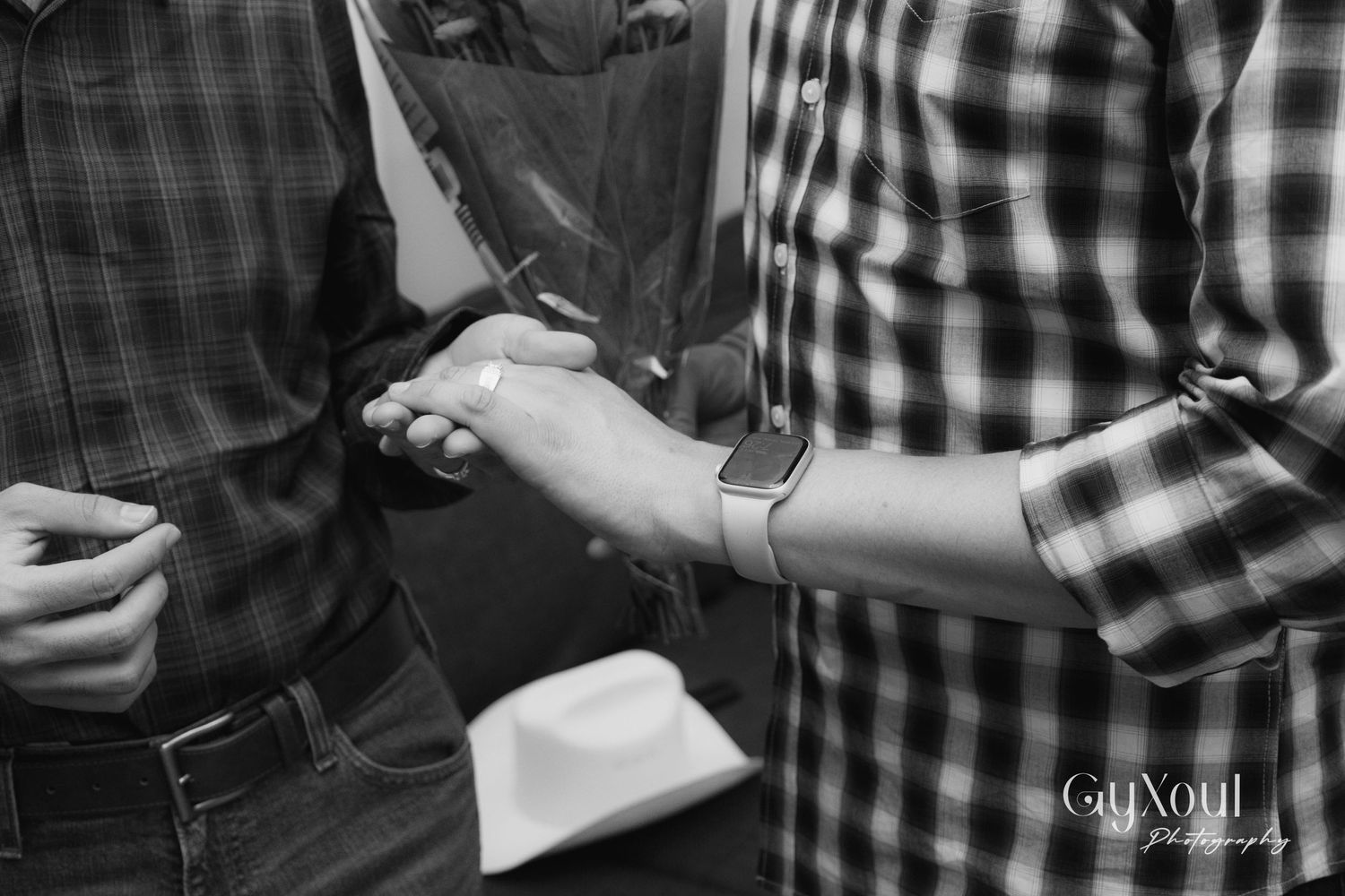 Black and white detail shot of hands exchanging rings or jewelry.