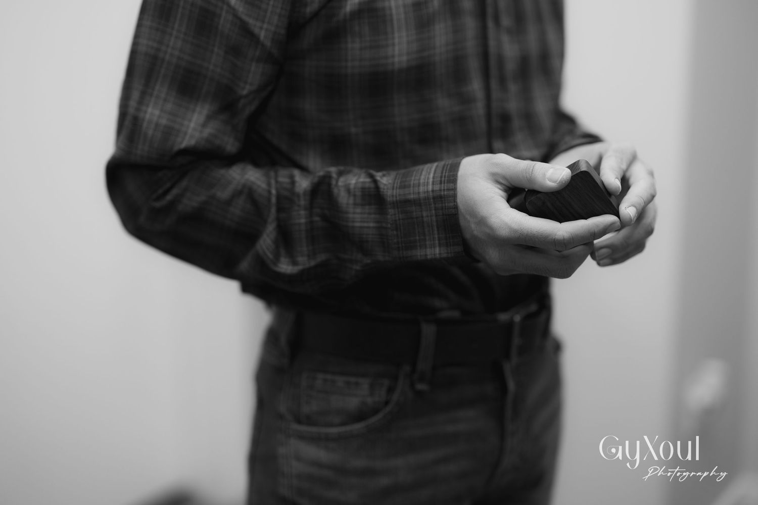 Close-up black and white photo of hands holding a small box or ring case.