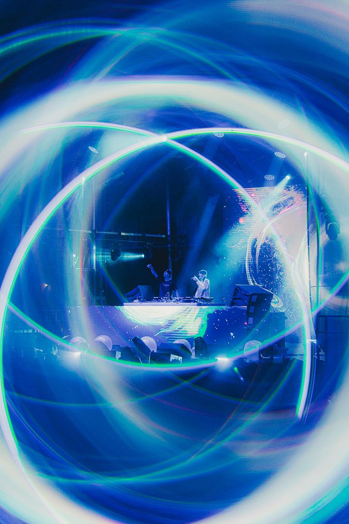 Abstract light trails create swirling blue and white patterns in a dark environment.