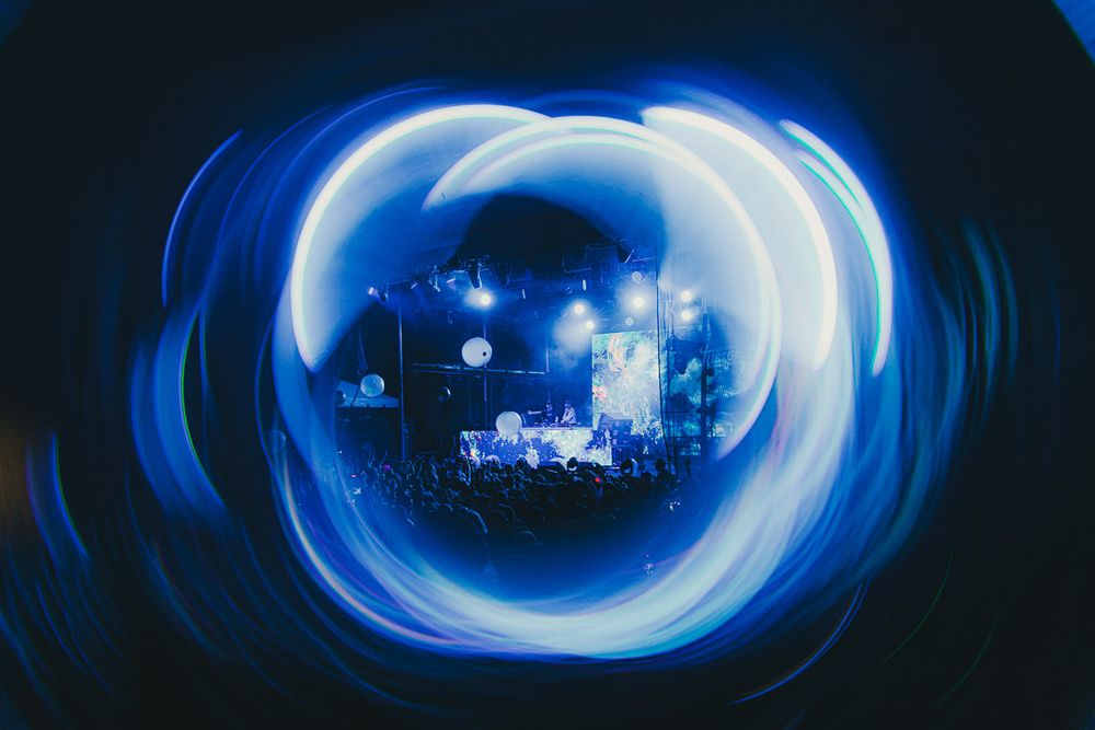 Abstract blue light trails creating circular patterns in a dark concert venue.