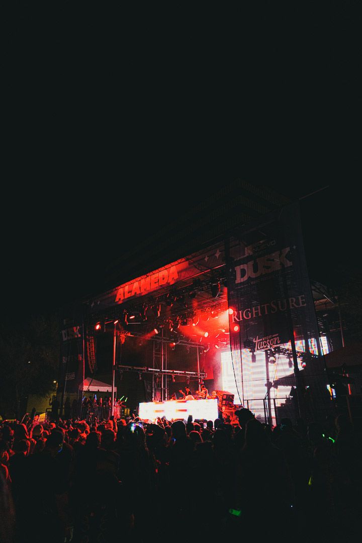 Concert crowd silhouetted against dramatic red stage lighting and smoke effects during a nighttime performance.