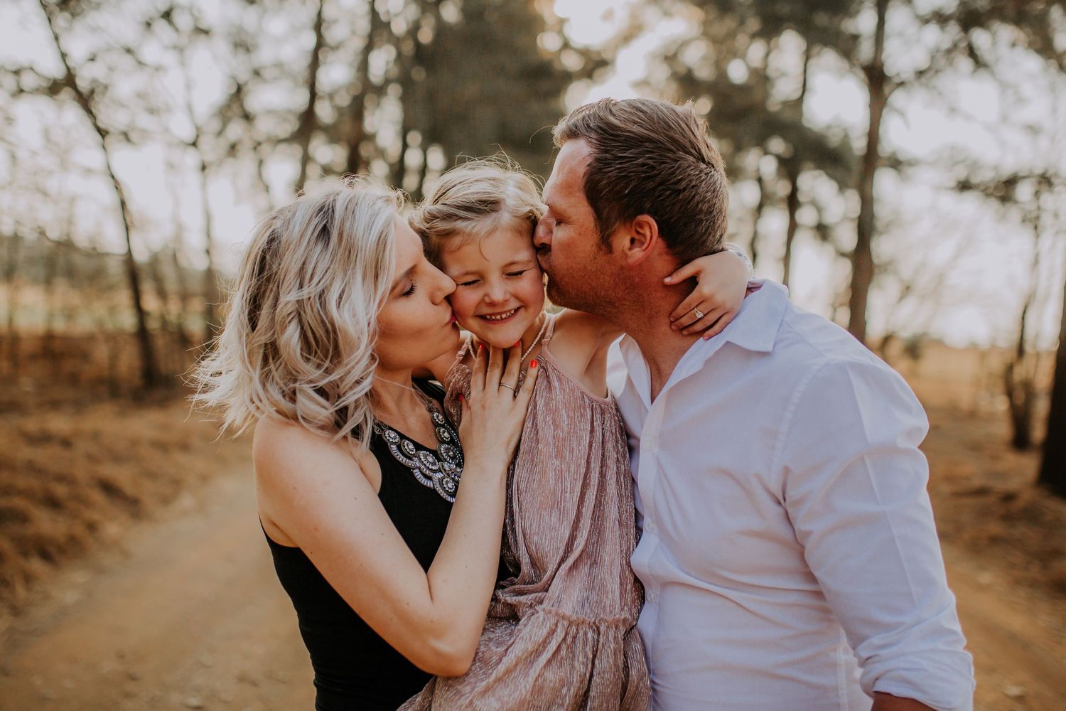 Family shares tender moments together during golden hour photoshoot in a rustic outdoor setting.