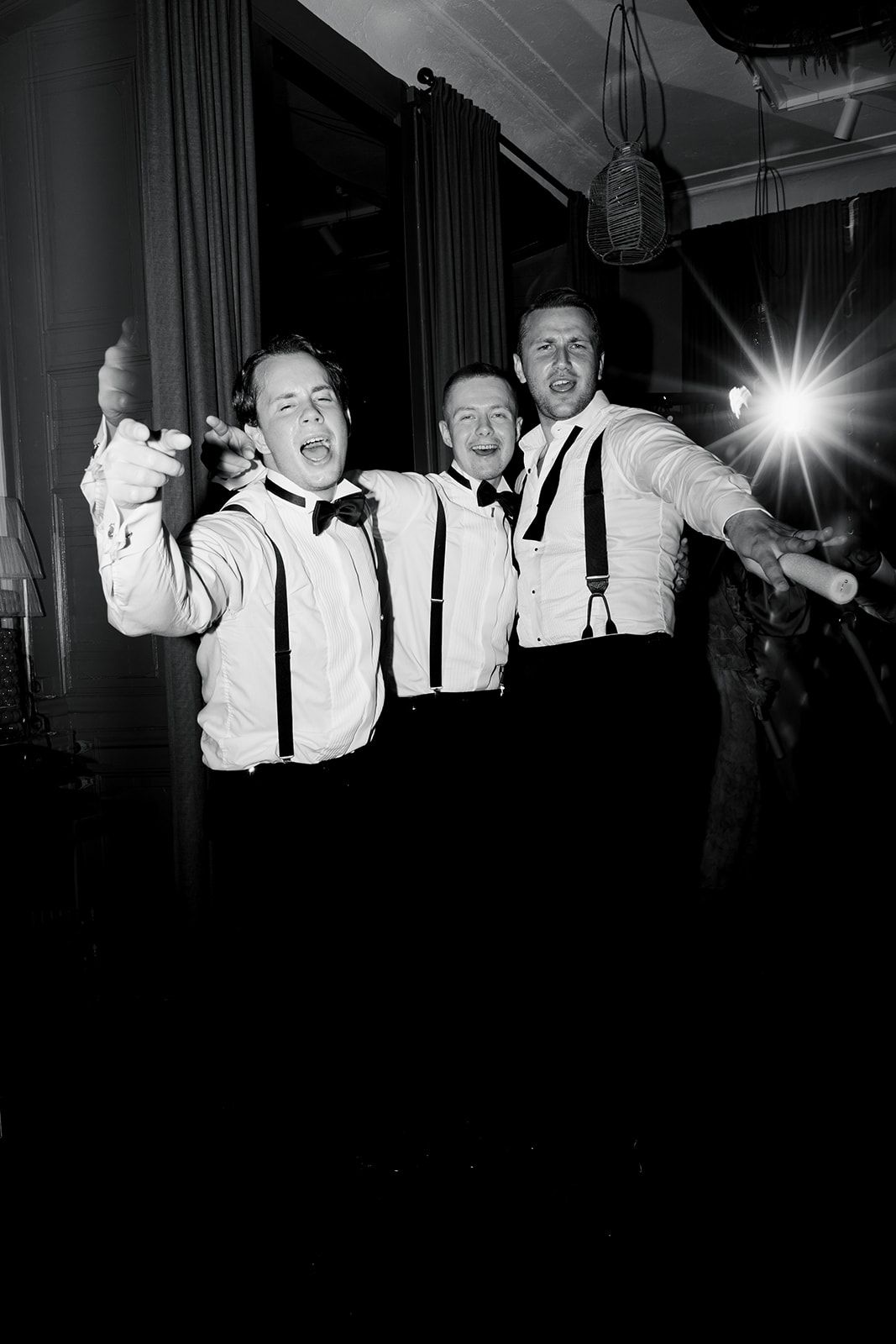 Wedding guests in black and white attire dance and celebrate on the reception dance floor during an evening celebration.