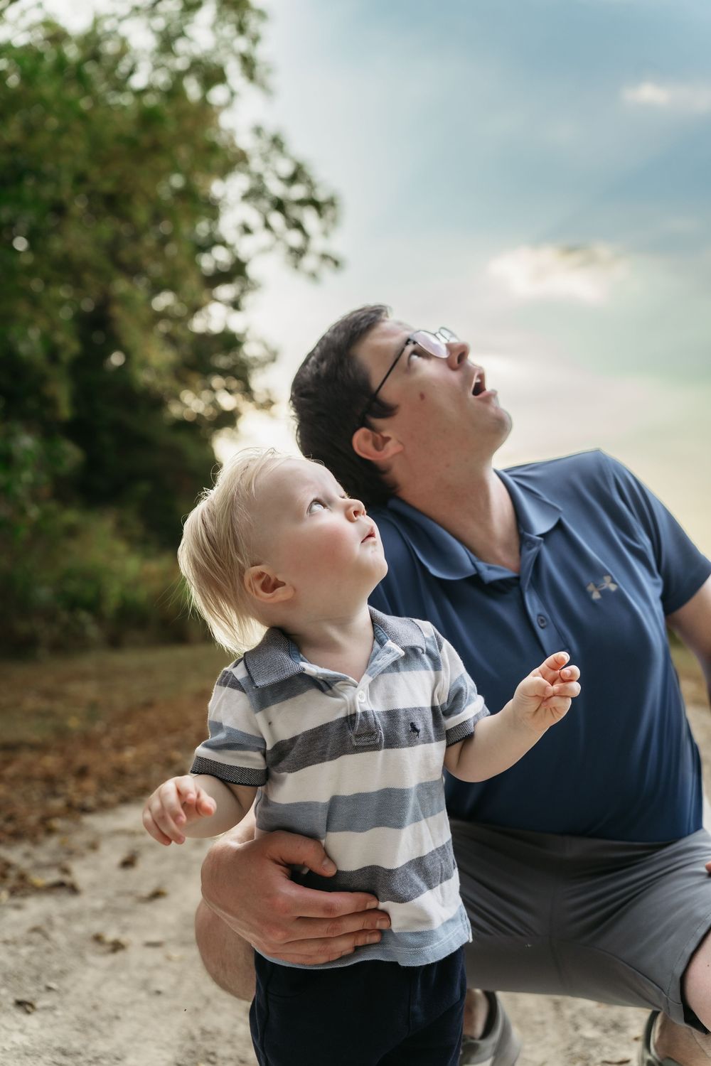Parent and child laugh together while looking up at the sky during a playful outdoor moment in Delaware, Ohio Family Photo Session