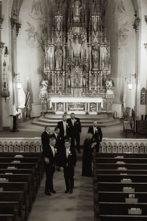 Black and white photo of church interior with wedding party gathered near altar.
