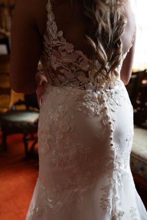 Detailed view of delicate lace appliques on a fitted white wedding dress.