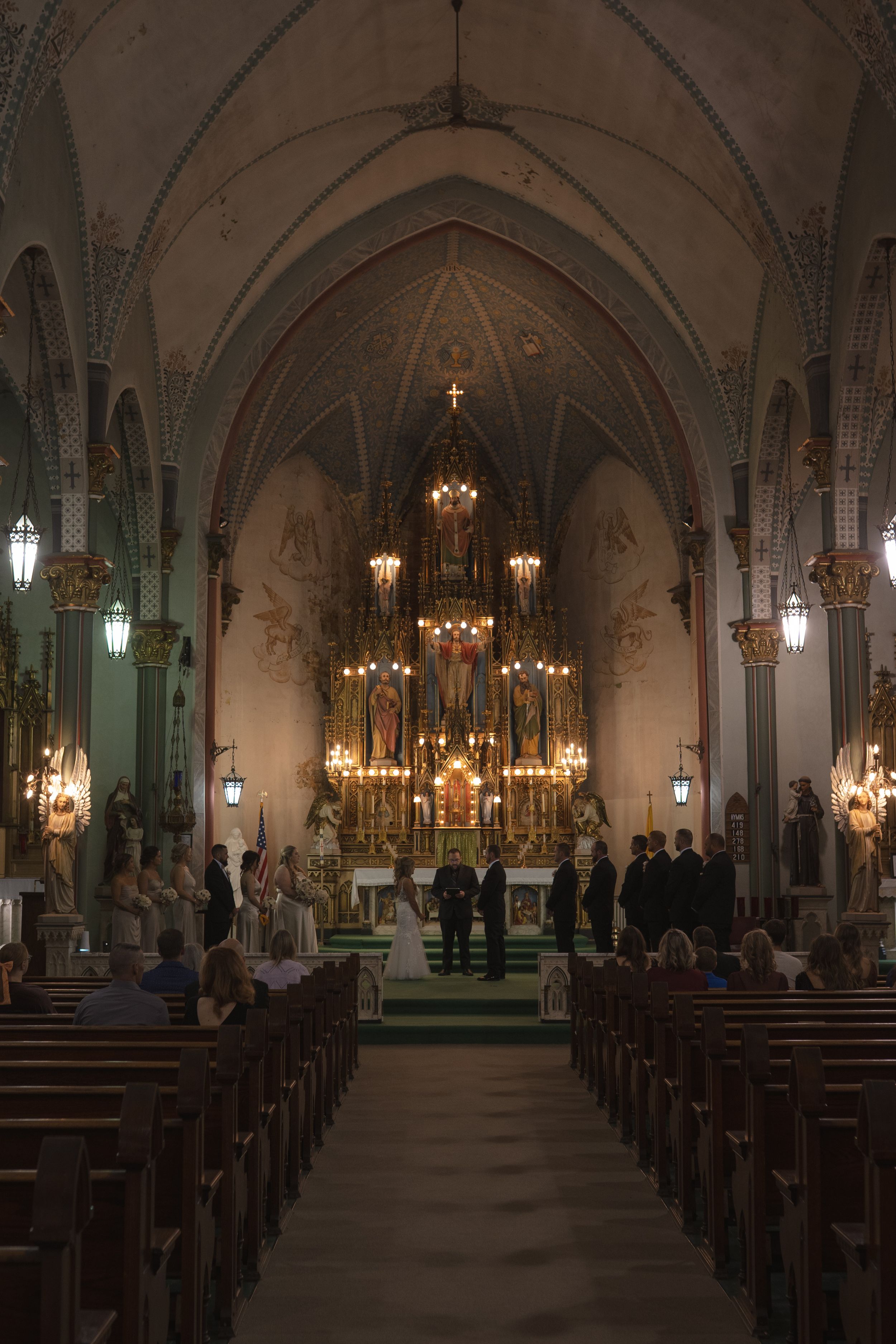 Interior of a gothic church with vaulted ceilings and ornate chandeliers during a wedding ceremony.