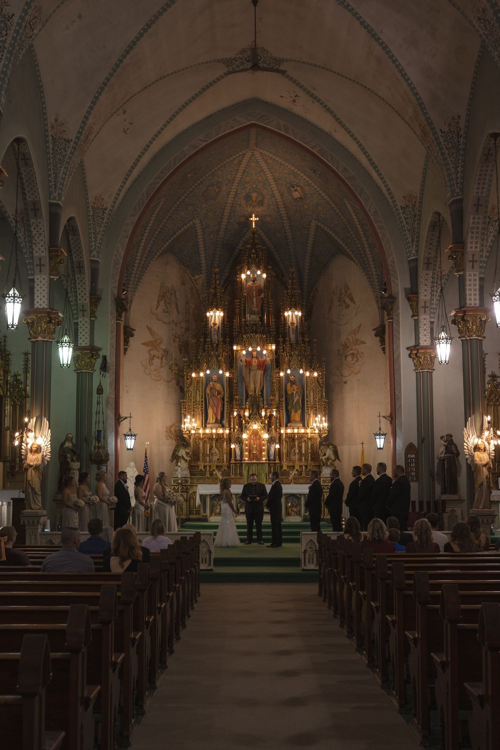 Interior of a gothic church with vaulted ceilings and ornate chandeliers during a wedding ceremony.