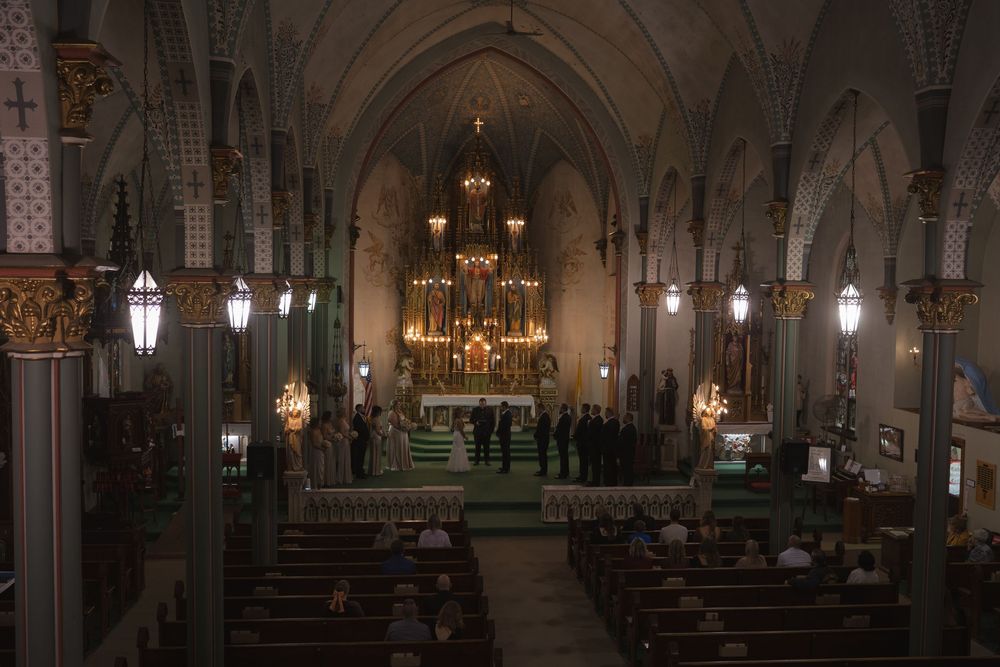 Atmospheric view of a church interior with gothic architecture and glowing chandeliers during a ceremony.