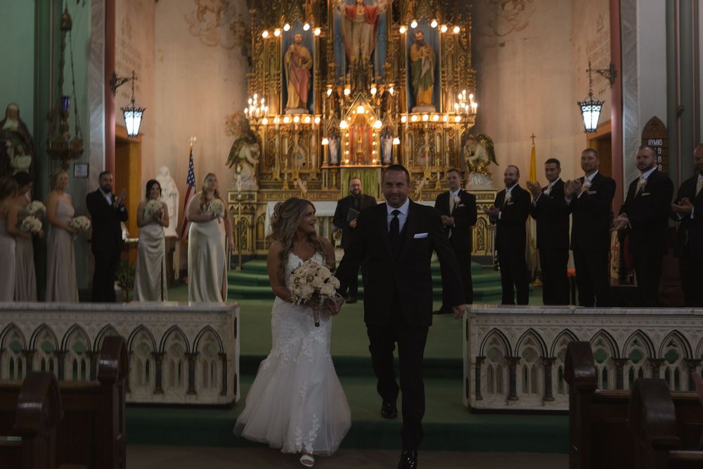 Wedding ceremony in a beautiful church with ornate altar and chandeliers.