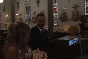 Wedding ceremony moment in a church with stained glass windows and traditional decor.