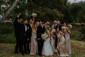 Wedding party members pose together in celebratory mood against autumn foliage.