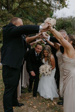 Wedding party joins hands in a coordinated pose during outdoor photo session.