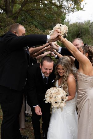 Wedding party joining hands in a circle formation outdoors during autumn.
