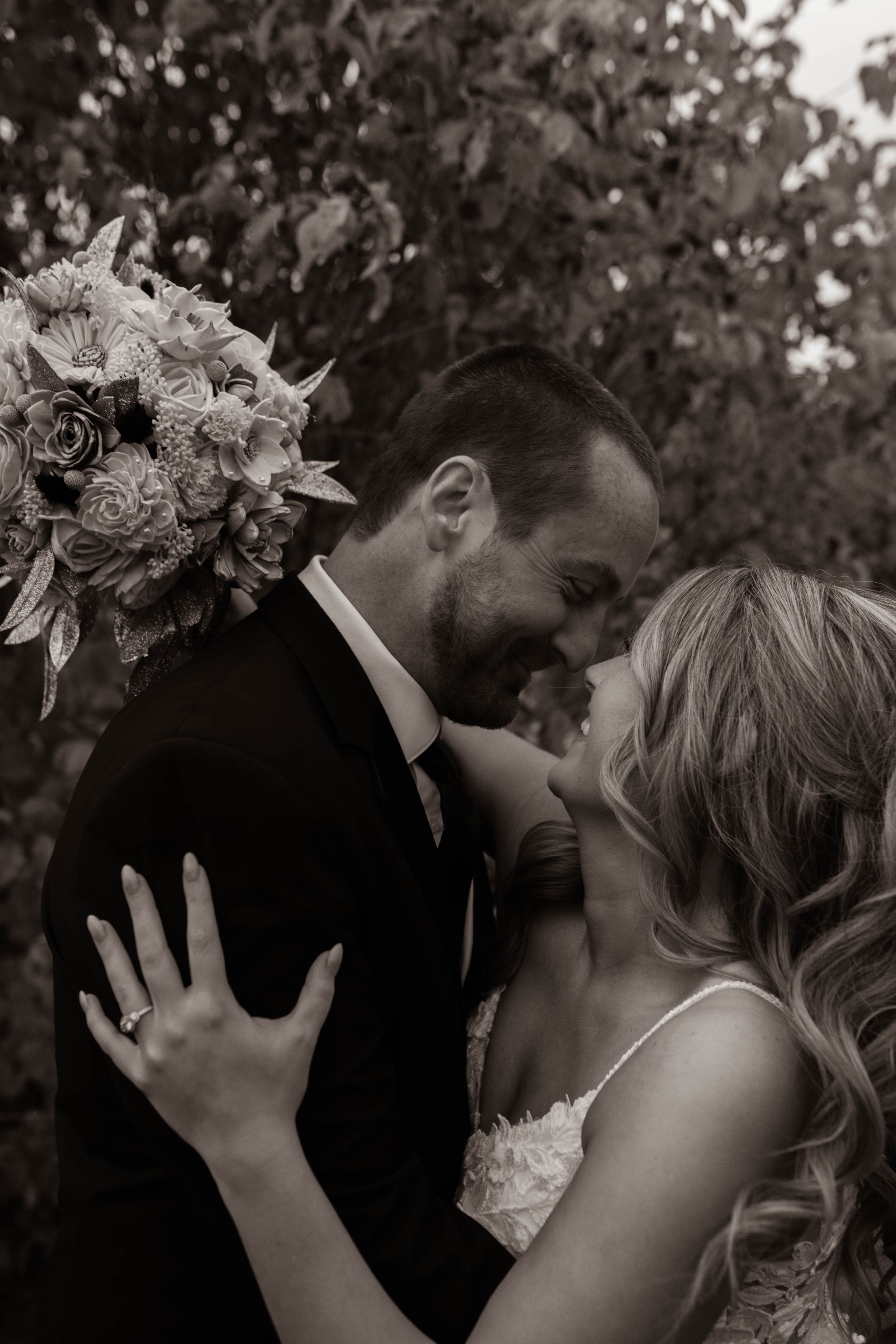 Artistic black and white wedding photograph capturing tender moment between couple.
