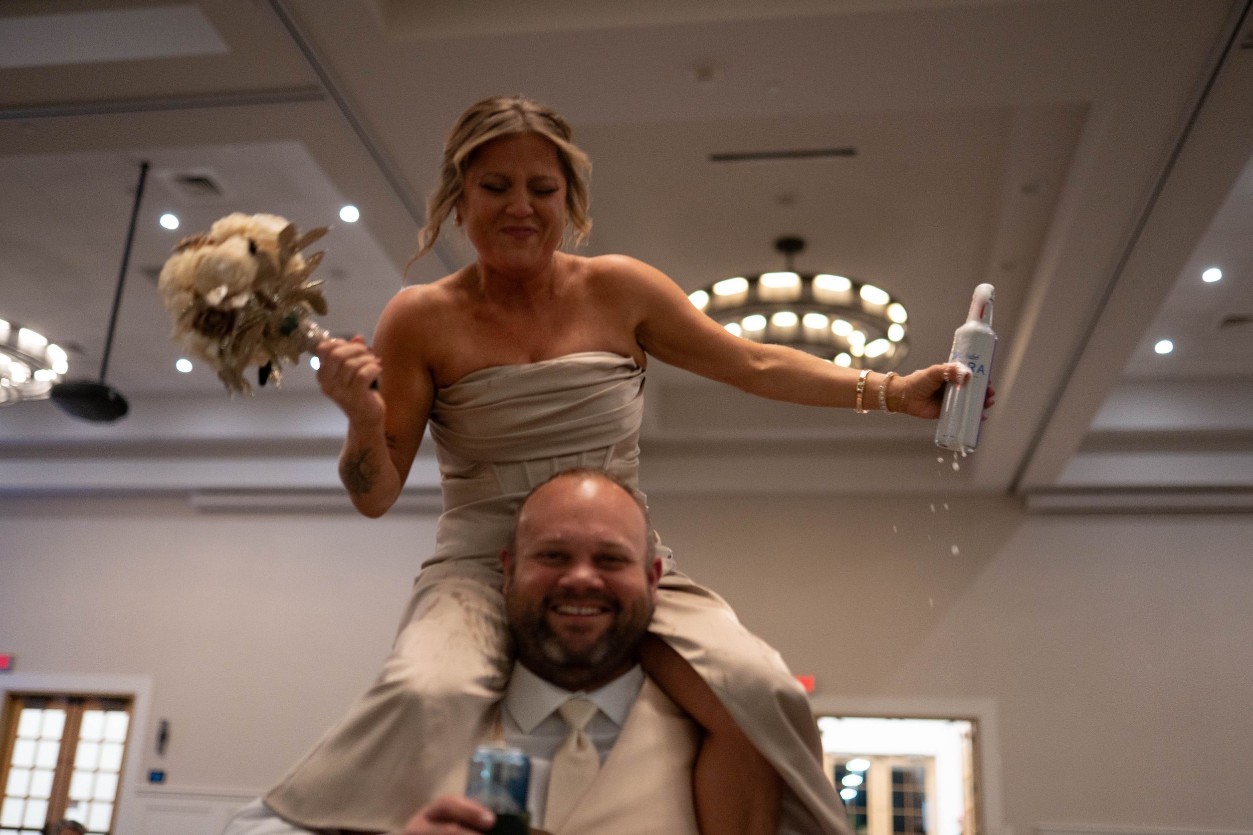 Joyful wedding reception moment with couple celebrating in a chandelier-lit ballroom.