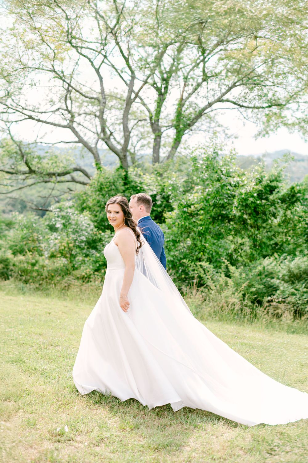 Bride and groom share romantic moments in a lush outdoor garden setting with flowing white wedding dress.
