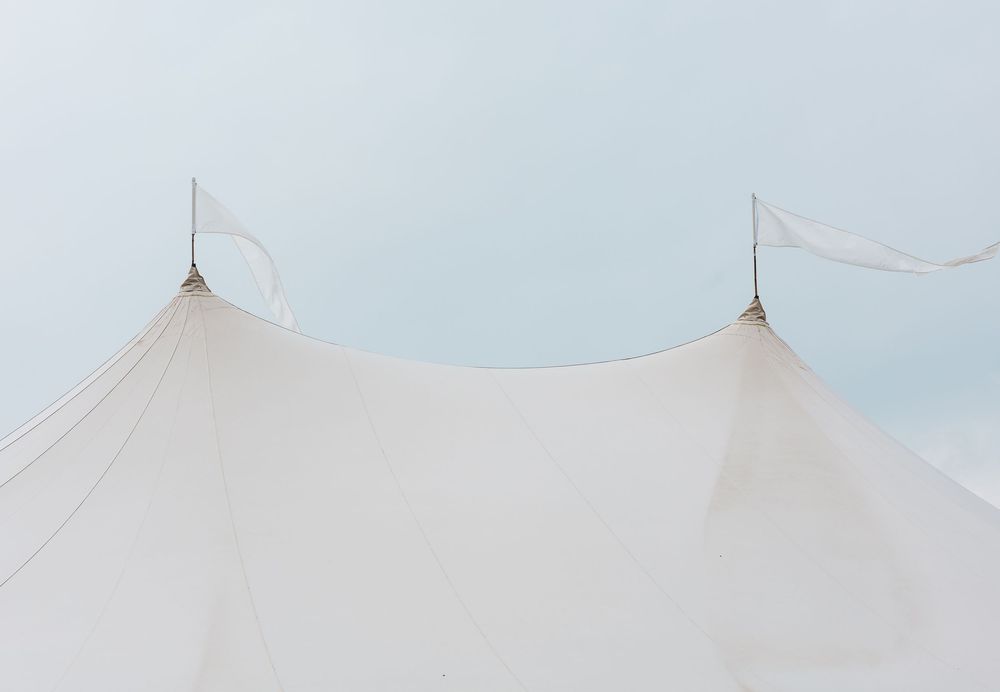 White tent canopy with two poles against a pale blue sky, ideal for outdoor events and weddings.