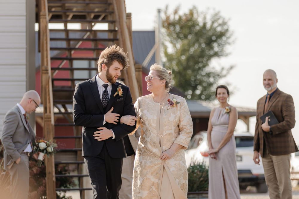 Wedding guests share emotional reactions and embraces during an outdoor ceremony.
