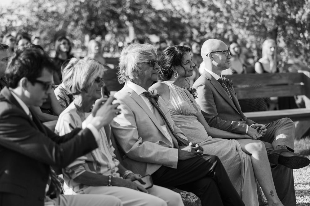 Black and white photo of wedding guests seated outdoors during a ceremony.