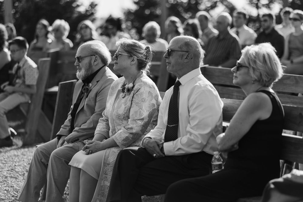 Black and white photograph of spectators sitting in stadium bleachers during an outdoor event.