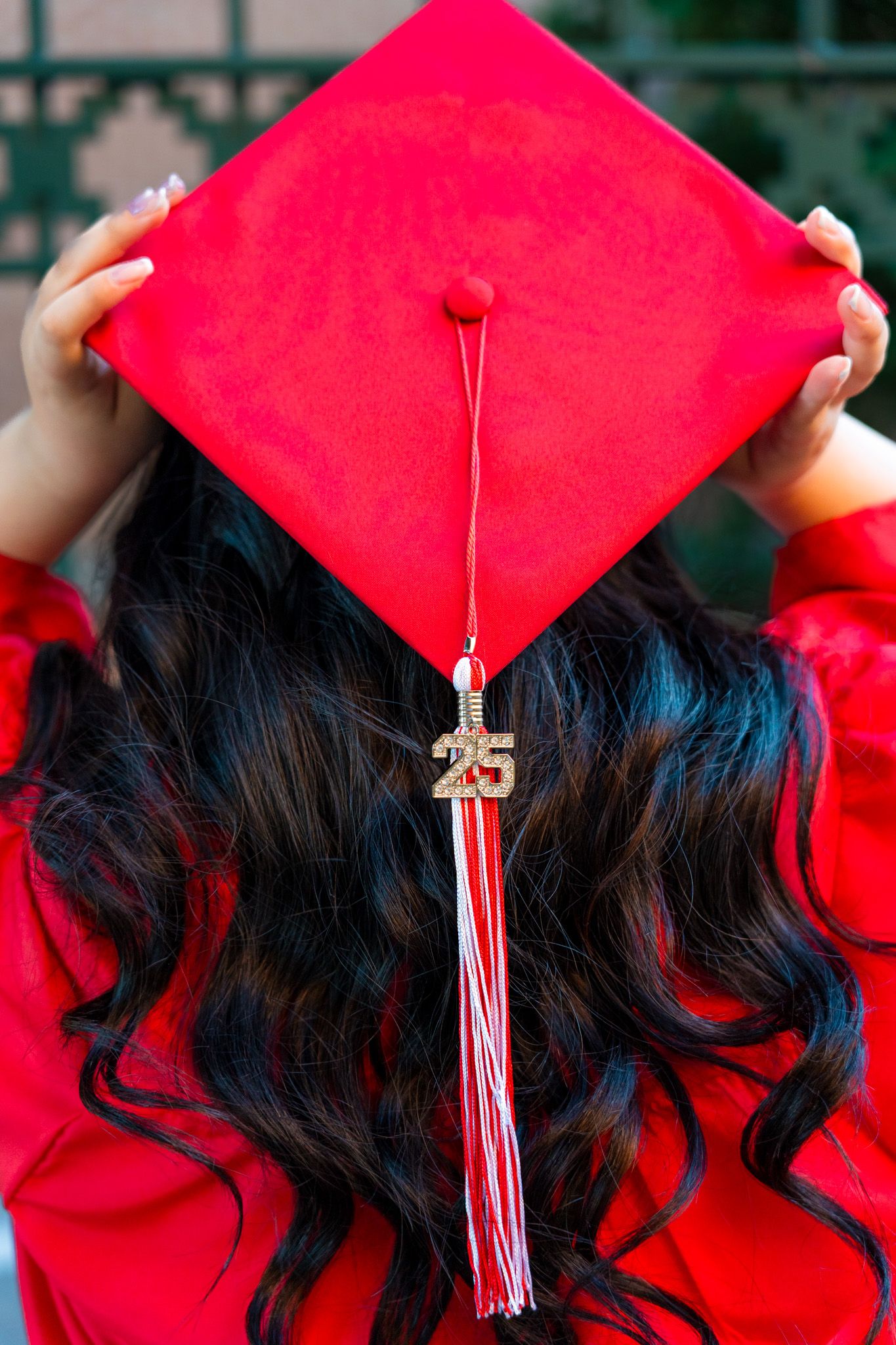 Close-up of red graduation cap with tassel against dark hair background.