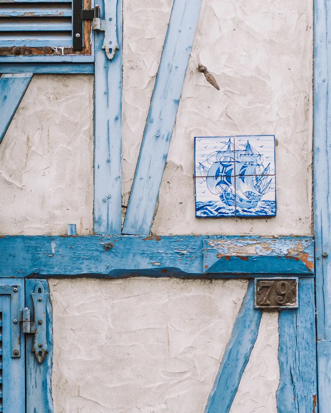 Close-up of blue timber-frame wall with a decorative ceramic tile detail.