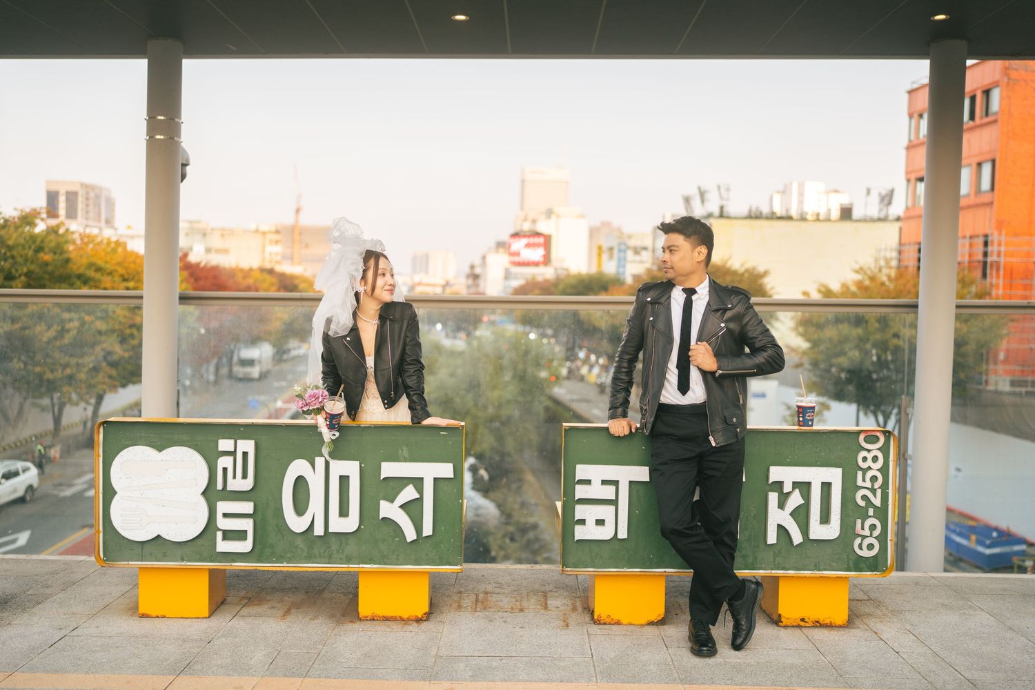 A person walks past yellow bollards and signage along a concrete wall in an urban setting.