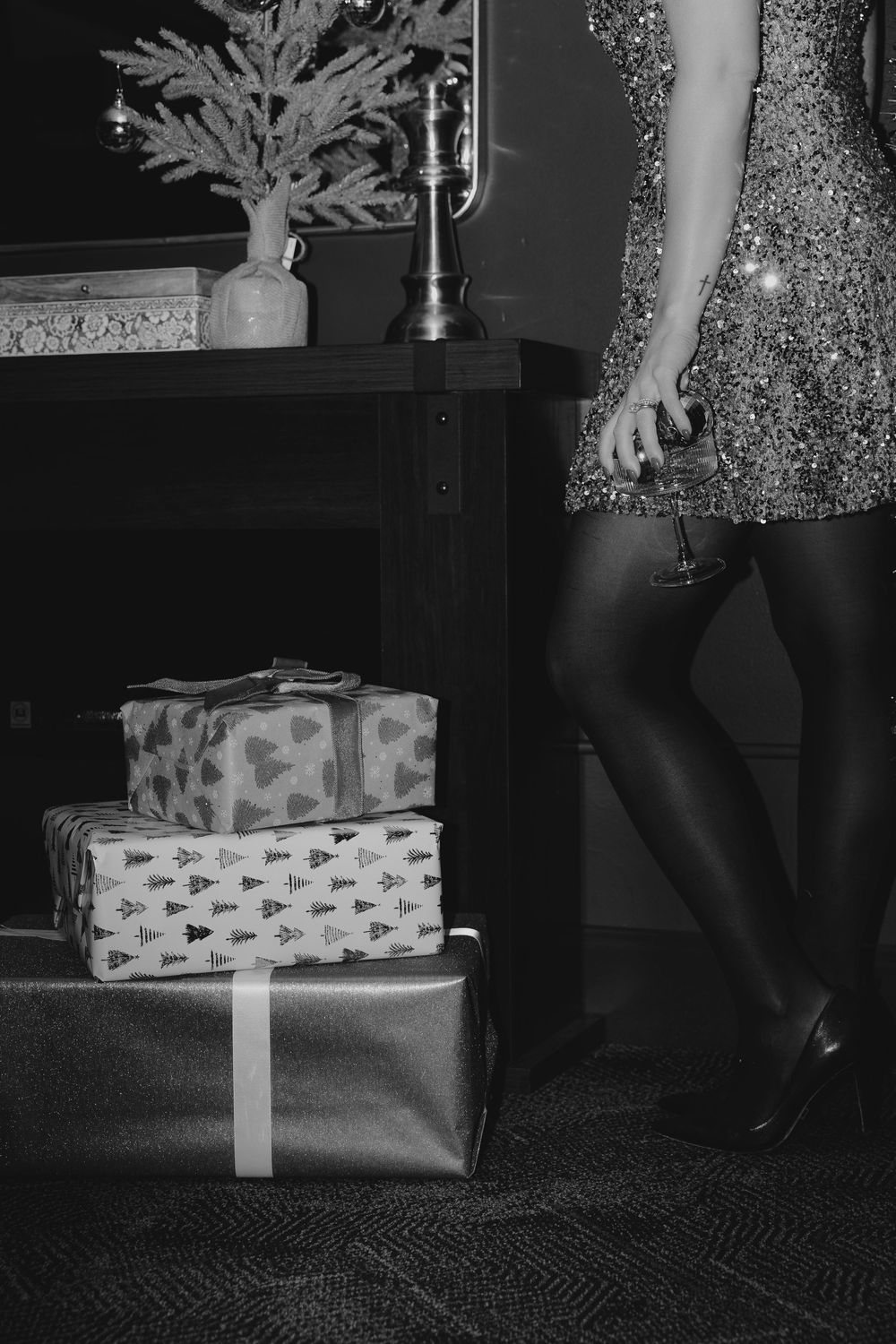 A sequence of black and white photos showing someone opening a wrapped gift box on a carpeted floor.