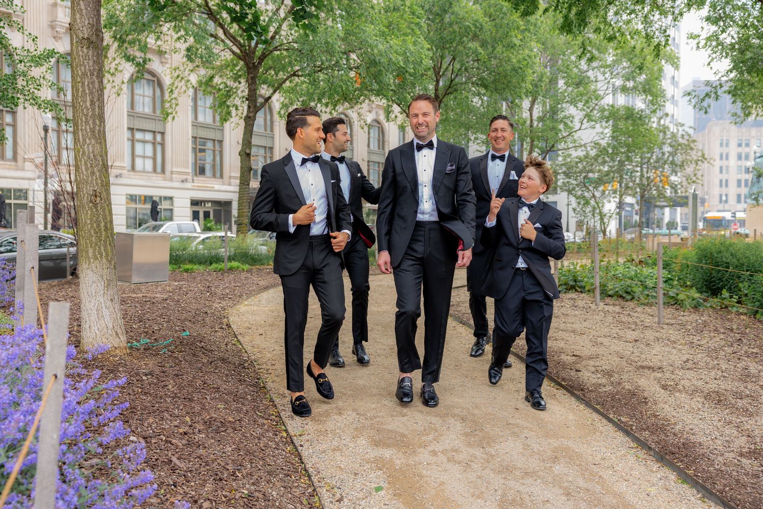 Groom and his groomsmen walking and laughing in front of the Bok Tower in detroit