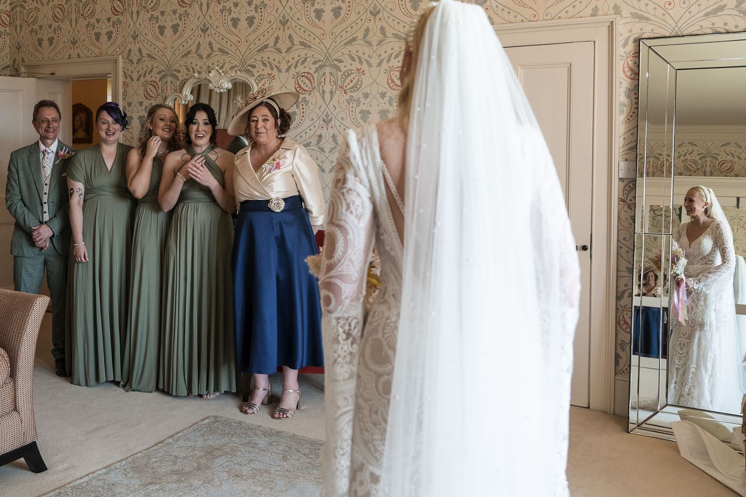 Bride revealing her wedding dress to bridesmaids in the Hodsock Priory Honeymoon Suite