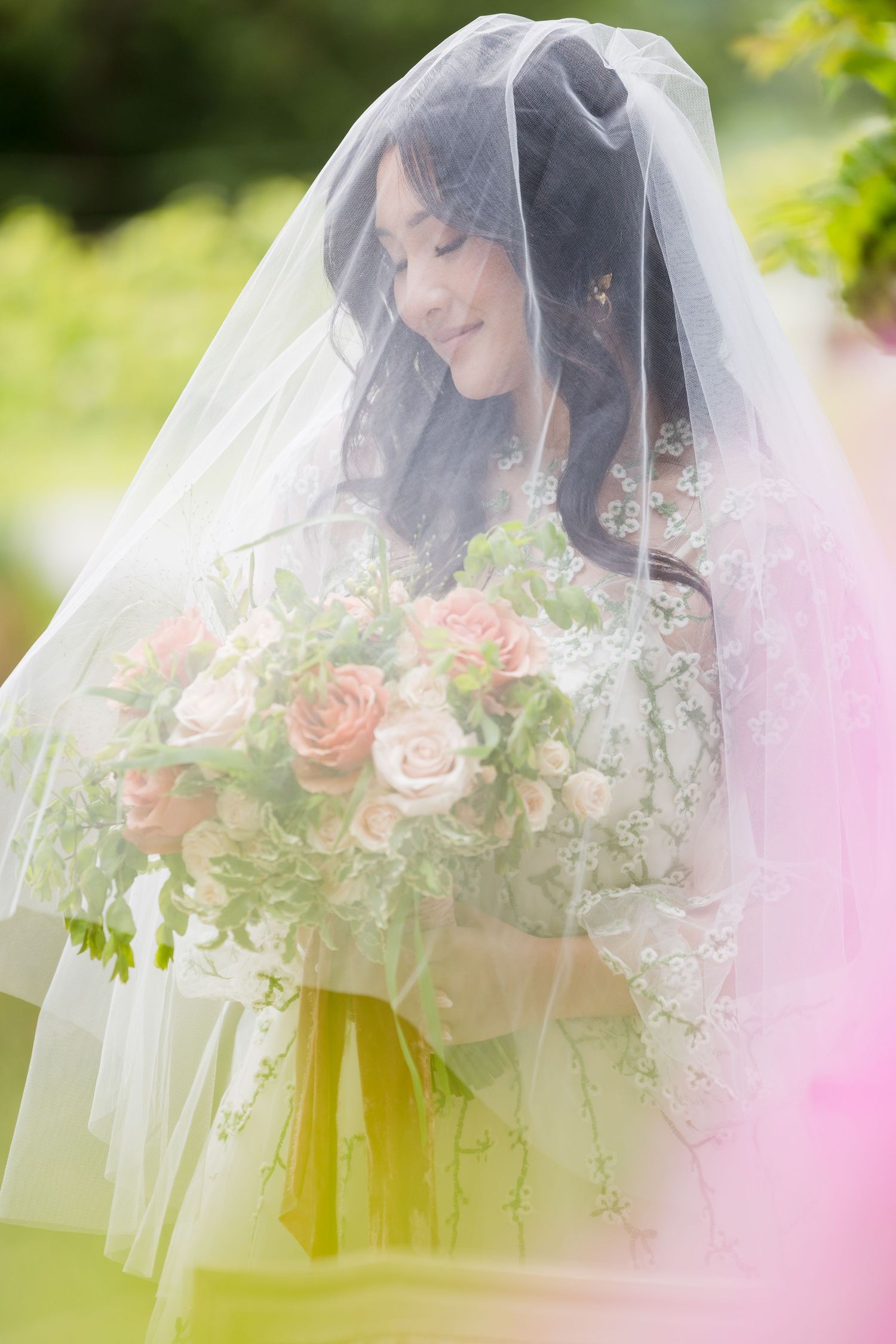 A wedding party poses together on outdoor steps surrounded by greenery and flowers.
