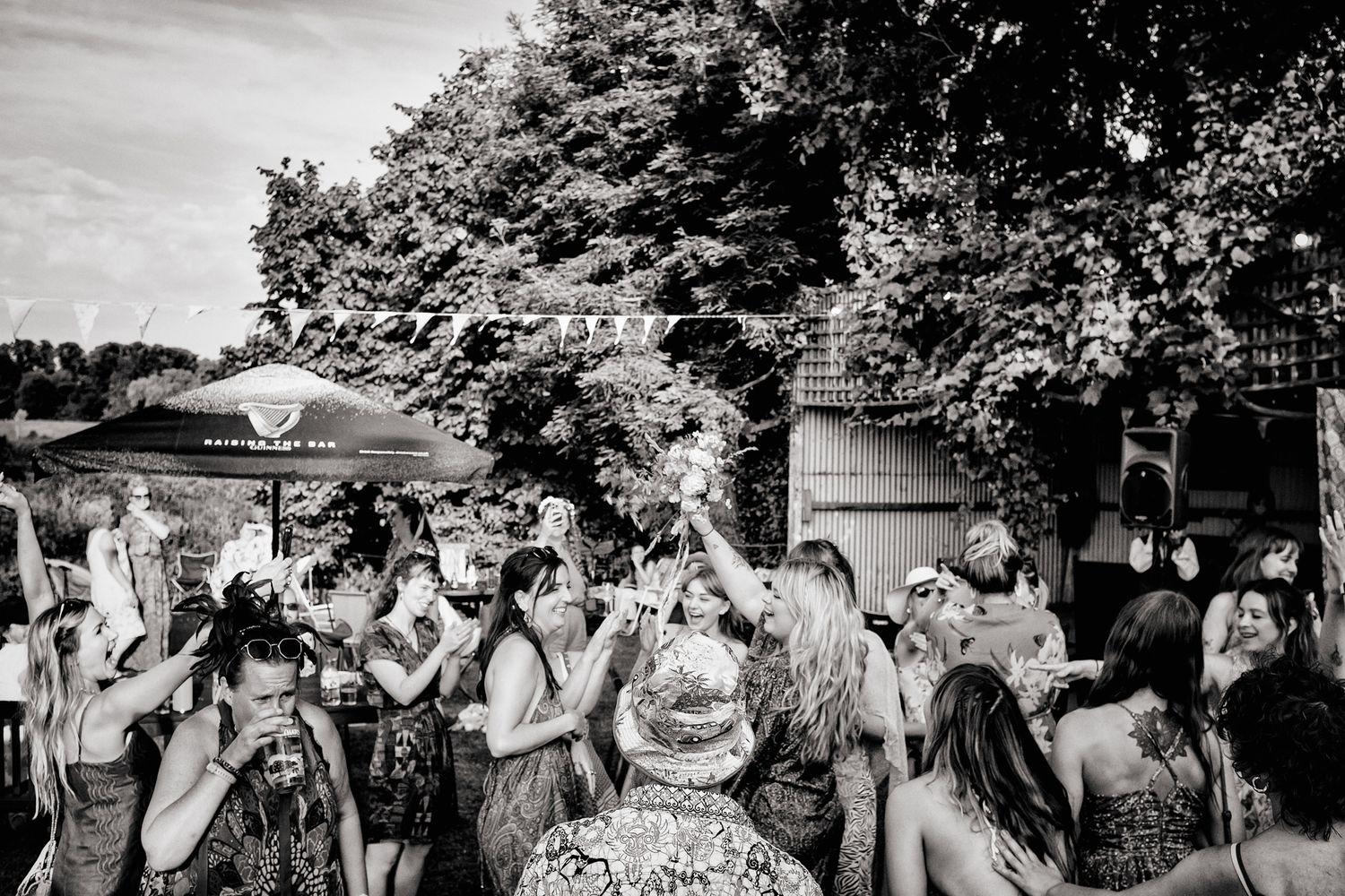 A crowd of people gathered outdoors at a summer festival in black and white photography.